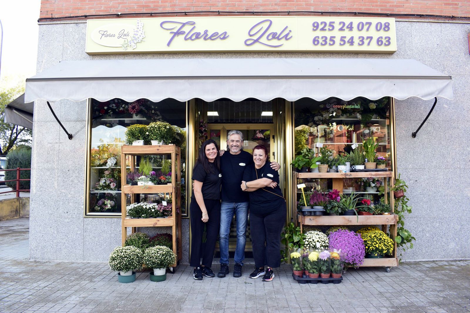 Fachada de Flores Loli con el equipo en la puerta y plantas de temporada en el escaparate